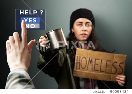 Female hand push a virtual button to the help. On the background defocused woman holds a cardboard sign with the text homeless and steel cup. The concept of helping the vagrants Female hand push a virtual button to the help. On the background defocused woman holds a cardboard sign with the text homeless and steel cup. The concept of helping the vagrants 90093484
