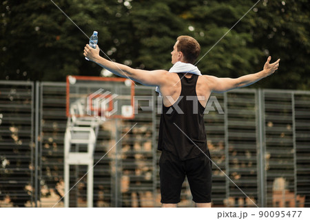 Muscular young man in sport clothes standing with hands aside on outdoor city gym 90095477