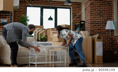 Homeowners couple decorating apartment flat with furniture after moving in, starting new beginnings together. Preparing to unpack things in household, home investment on loan. 90096199