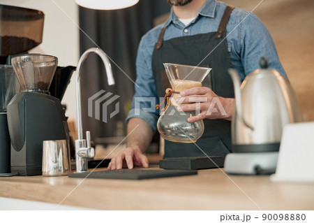 barista holds in his hands a glass vessel for making filter coffee barista holds in his hands a glass vessel for making filter coffee 90098880
