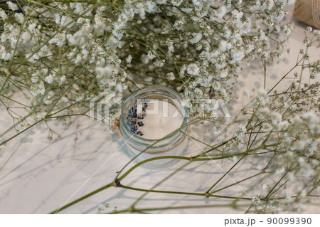 Candles made of soy wax with lavender in jars against the background of flowering gypsophila Candles made of soy wax with lavender in jars against the background of flowering gypsophila 90099390