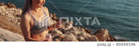 Smiling female resting after training by the waterfront 90099596