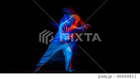 Astonished man, hip-hop dancer in sportive style clothes dancing isolated on dark background at dance hall in mixed neon light. Youth culture, hip-hop, movement Astonished man, hip-hop dancer in sportive style clothes dancing isolated on dark background at dance hall in mixed neon light. Youth culture, hip-hop, movement 90099811