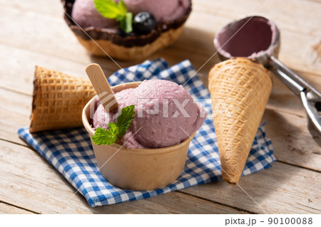Blueberry ice cream scoops with waffle on wooden table 90100088