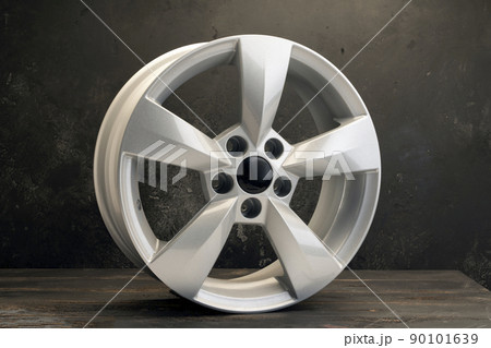 new grey alloy wheels on a dark textured black background. a wheel for a car new grey alloy wheels on a dark textured black background. a wheel for a car 90101639