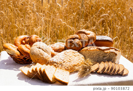 lot of different flavored bread, wheat, rye, on the table in the field outside lot of different flavored bread, wheat, rye, on the table in the field outside 90103872