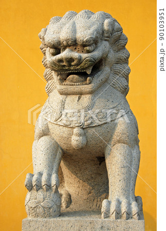 Zhenjiang, Jiangsu Province, China: A traditional Chinese lion statue against a yellow background at Dinghui Temple in Zhenjiang. 90103951