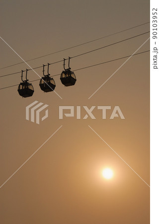 Sihouette of cable cars against the sky with evening sun. 90103952