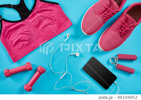 Flat lay shot of Sport equipment. Sneakers, dumbbells, earphones and phone on blue background. 90104052