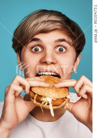 Very hungry young man holding tasty hamburger 90104751