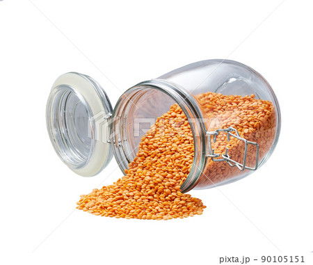 Raw red lentils spill out of a glass storage jar isolated on white background. Raw red lentils spill out of a glass storage jar isolated on white background. 90105151