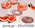 Champagne, rose sparkling wine or paloma cocktails in crystal glasses on pink background with pieces citrus . Refreshing beverage with grapefruit slice and mint. Summer drinks, selective focus 90105666