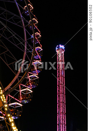 Ferris Wheel Lights at Night. Neon colored lights flashing on the Ferris wheel. Amusement park at night. Entertainment and fun. Recreation carousel at carnival. 90106502