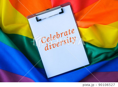 Rainbow flag with text CELEBRATE DIVERSITY message paper note. Rainbow lgbtq flag made from silk material. Symbol of LGBTQ pride month. Equal rights 90106527