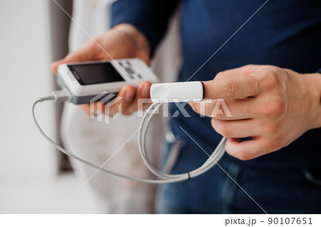Man using finger pulse oximeter, healthcare monitoring concept. Pulse oximeter on a white background 90107651