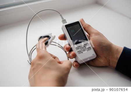 Man using finger pulse oximeter, healthcare monitoring concept. Pulse oximeter on a white background Man using finger pulse oximeter, healthcare monitoring concept. Pulse oximeter on a white background 90107654