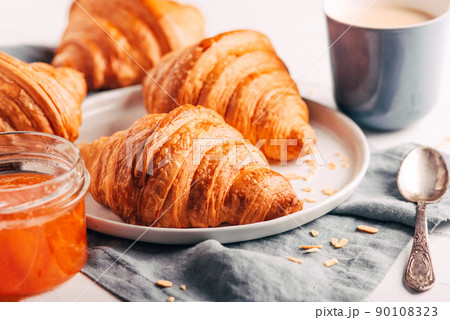 Plate with fresh croissants, jam and coffee on white wooden table. Close up. Plate with fresh croissants, jam and coffee on white wooden table. Close up. 90108323
