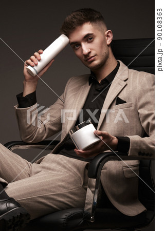Handsome man hairdresser in a suit with a cosmetic in his hands. Handsome man hairdresser in a suit with a cosmetic in his hands. 90108363