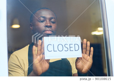 African male owner hanging closed sign on window of his cafe, he stopping work because of sanctions 90108615