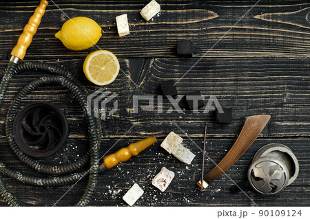 Arabic hookah with a tobacco flavor of a mixture of lemon. Top view of a dark wooden background Arabic hookah with a tobacco flavor of a mixture of lemon. Top view of a dark wooden background 90109124