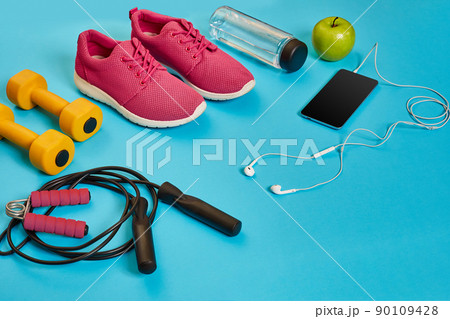 Flat lay of dumbbell, bottle of water, jump rope and sneaker, sport equipments, fitness items, top view 90109428