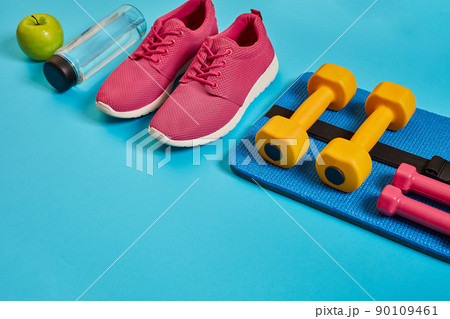 Healthy concept, diet plan with sport shoes and bottle of water and dumbbells on blue background, healthy food and exercise concept Healthy concept, diet plan with sport shoes and bottle of water and dumbbells on blue background, healthy food and exercise concept 90109461