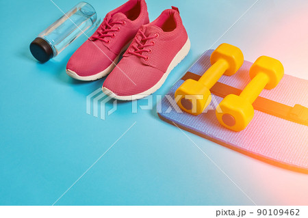 Healthy concept, diet plan with sport shoes and bottle of water and dumbbells on blue background, healthy food and exercise concept. Sun flare Healthy concept, diet plan with sport shoes and bottle of water and dumbbells on blue background, healthy food and exercise concept. Sun flare 90109462
