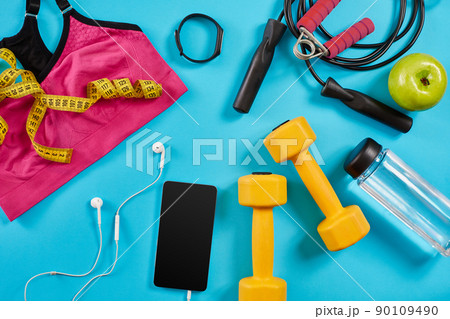 Athlete's set with female clothing, dumbbells and bottle of water on bright blue background Athlete's set with female clothing, dumbbells and bottle of water on bright blue background 90109490