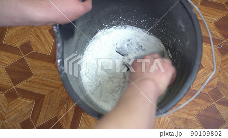 The builder mixes the putty with water in the repair bucket. 90109802