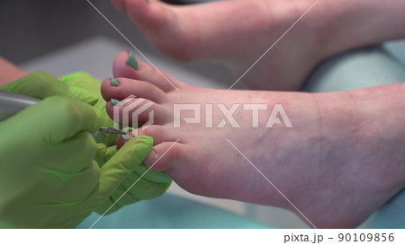 A professional pedicurist performs the procedure for removing old toenails. Girl in salon close-up. A professional pedicurist performs the procedure for removing old toenails. Girl in salon close-up. 90109856