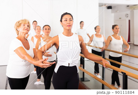 Elderly ballet instructor adjusting students form 90111884