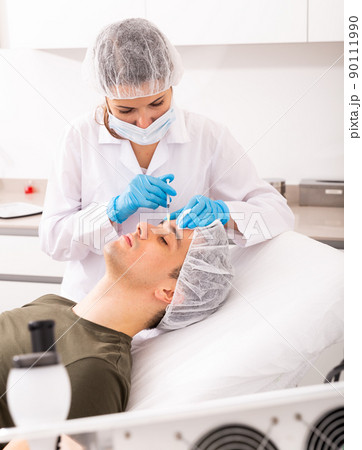 Man getting face injections at aesthetic clinic Man getting face injections at aesthetic clinic 90111990