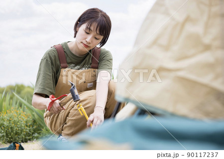 テント設営をする若いキャンプ女子 ペグ打ち テント設営をする若いキャンプ女子 ペグ打ち 90117237