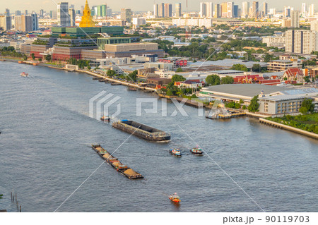 Cargo and sand ships pass the new Thai parliament on the Chao Phraya River in the evening. 90119703