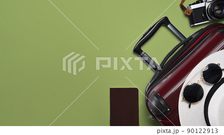 Suitcase, smart phone, sunglasses, camera and passport on green background for summer holidays. Top view with copy space Suitcase, smart phone, sunglasses, camera and passport on green background for summer holidays. Top view with copy space 90122913