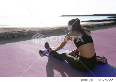 Beautiful girl stretching in front of the beach after exercising. Beautiful girl stretching in front of the beach after exercising. 90124722