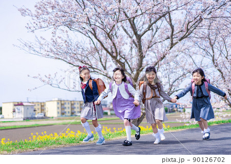 ランドセルを背負って楽しく登校する小学生の女の子たち 90126702