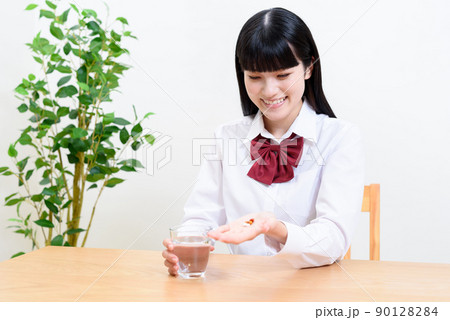 コップの水で薬を飲む女子高校生　コップの水と薬、錠剤、サプリ　 90128284