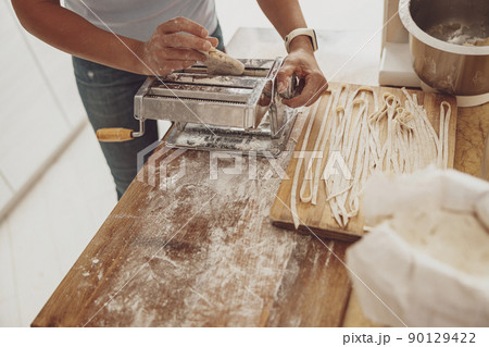 Cooking homemade noodles by a woman with a noodle cutter in the background of the kitchen Cooking homemade noodles by a woman with a noodle cutter in the background of the kitchen 90129422