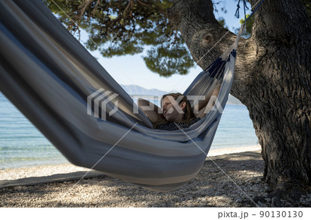 Young woman relaying and enjoying in a hammock by the beach Young woman relaying and enjoying in a hammock by the beach 90130130