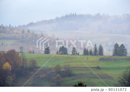 Cloudy and foggy autumn mountains scene. Peaceful picturesque traveling, seasonal, nature and countryside beauty concept scene. Carpathian Mountains, Ukraine. 90131072