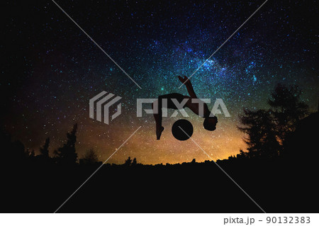 sporty man jumping silhouette at the night starry sky and moon background. sporty man jumping silhouette at the night starry sky and moon background. 90132383