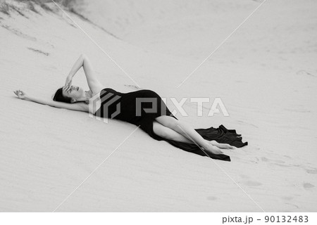 girl in a black long dress in a sandy desert girl in a black long dress in a sandy desert 90132483