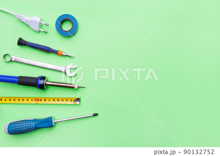 Repair tools on a green background. Measuring tape, screwdriver, soldering iron. Place for text. Copy space. Flat lay. Top view. Handyman tool kit. DIY. Advertising for the store. 90132752