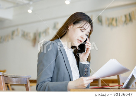 資料を見ながら問い合わせをする女性 90136047