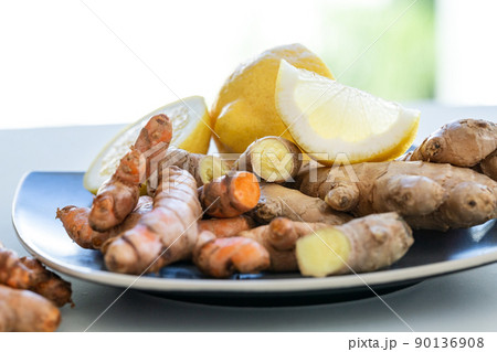 Roots of ginger and turmeric with lemon on plate Roots of ginger and turmeric with lemon on plate 90136908