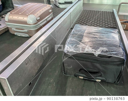 baggage on the tape at the airport. the suitcase travels along the line. things are stacked. the suitcase is packed in a transparent film. safety and security of personal belongings baggage on the tape at the airport. the suitcase travels along the line. things are stacked. the suitcase is packed in a transparent film. safety and security of personal belongings 90138763