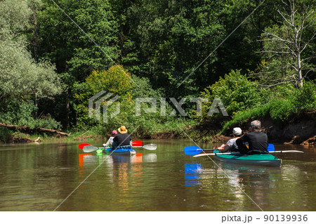 Family kayak trip. Man and woman and elderly couple senior and seniora rowing boat on the river, a water hike, a summer adventure. Eco-friendly and extreme tourism, active and healthy lifestyle Family kayak trip. Man and woman and elderly couple senior and seniora rowing boat on the river, a water hike, a summer adventure. Eco-friendly and extreme tourism, active and healthy lifestyle 90139936