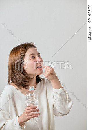 カプセル錠剤を飲む若い女性 90140376