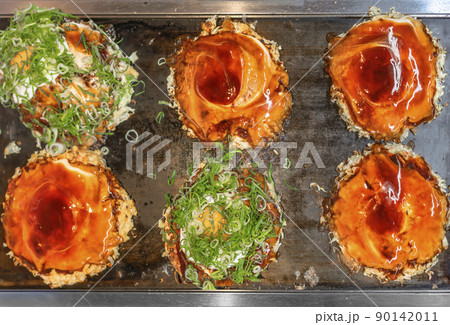 [国内] 鉄板で焼いてる目玉焼きとソースとネギを満遍なく乗せたお好み焼き 90142011